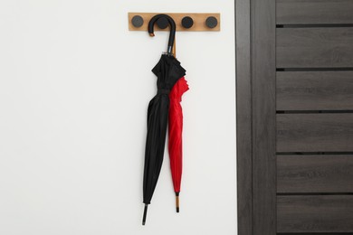 Photo of Black and red umbrellas on rack in hallway