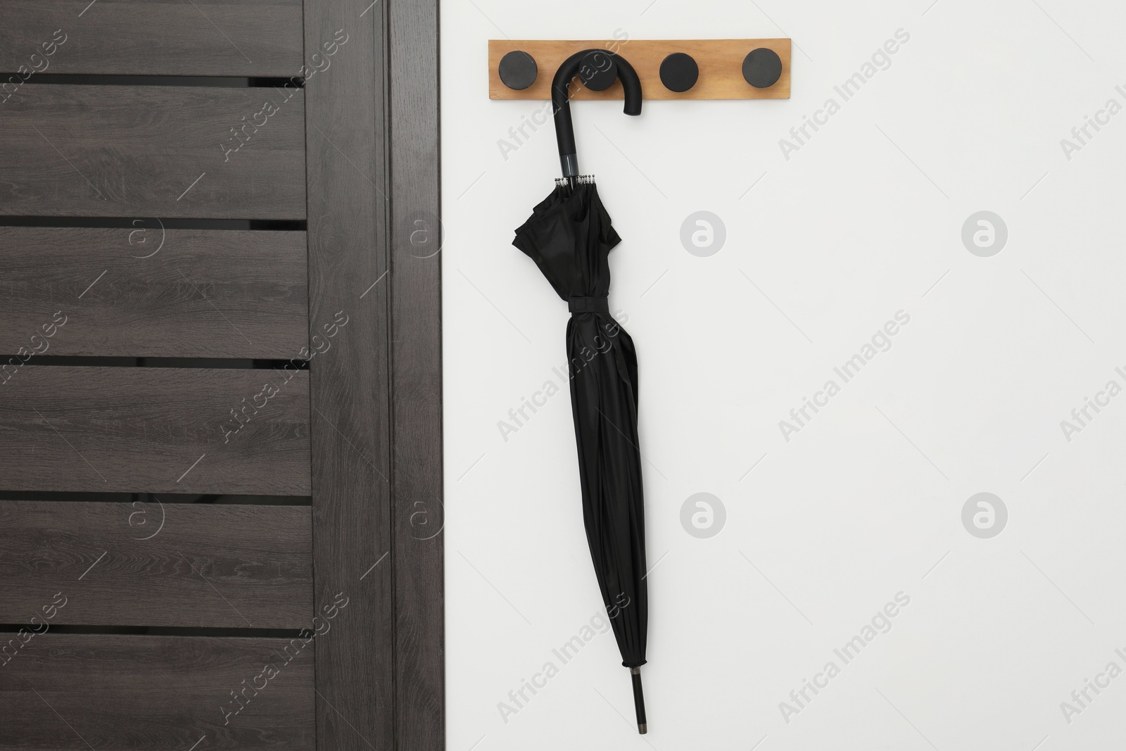 Photo of Black umbrella on coat rack in hallway