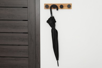 Black umbrella on coat rack in hallway