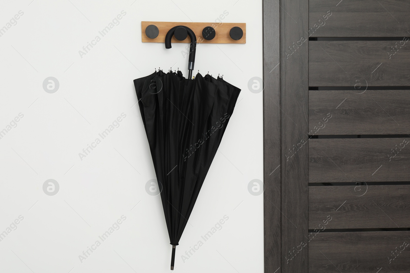 Photo of Black umbrella on coat rack in hallway