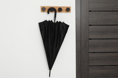 Black umbrella on coat rack in hallway