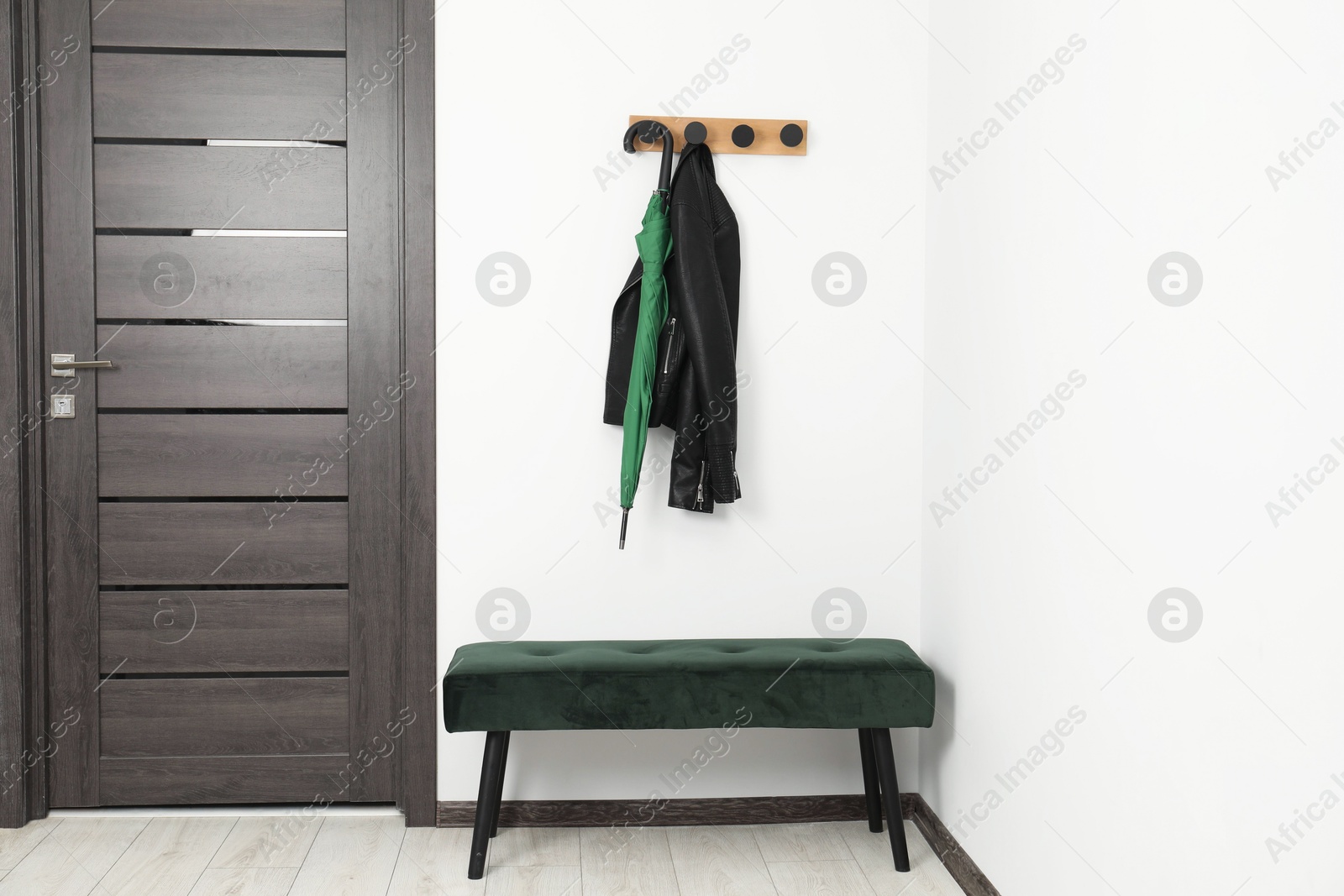 Photo of Green umbrella, leather jacket, rack and ottoman in hallway