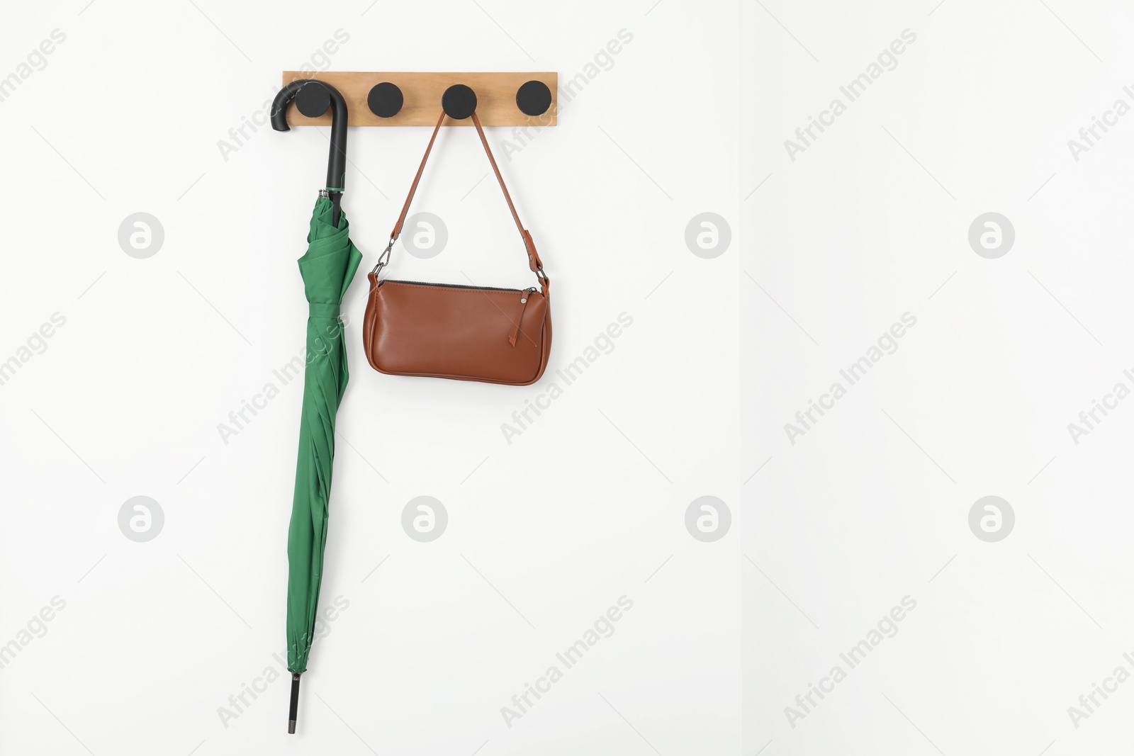 Photo of Green umbrella and bag on rack in hallway, space for text