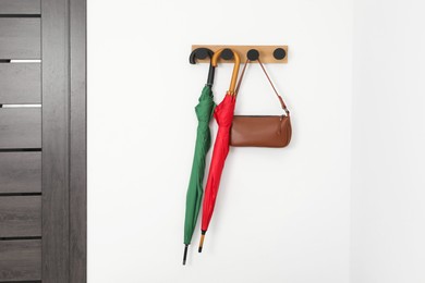 Colorful umbrellas and bag on rack in hallway