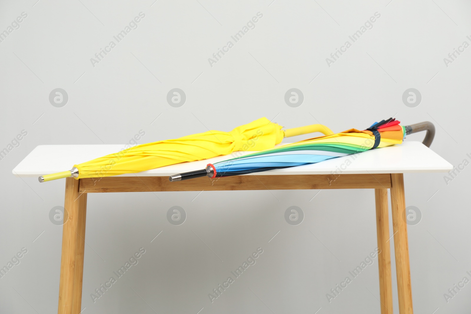 Photo of Colorful umbrellas on white table against light grey background