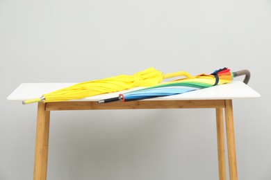 Colorful umbrellas on white table against light grey background