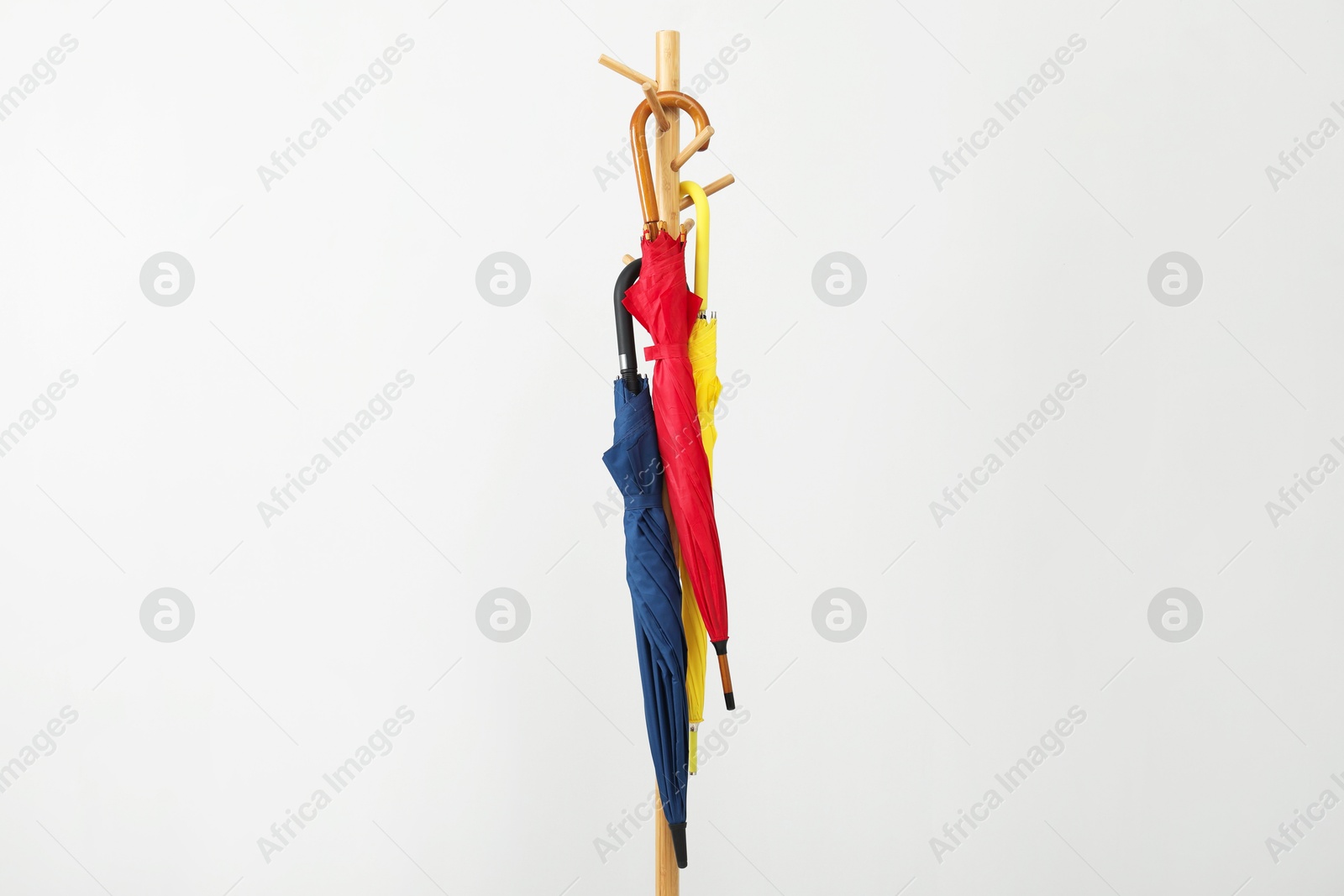 Photo of Colorful umbrellas on clothing rack against light grey background