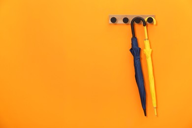 Colorful umbrellas on wooden rack in hallway, space for text