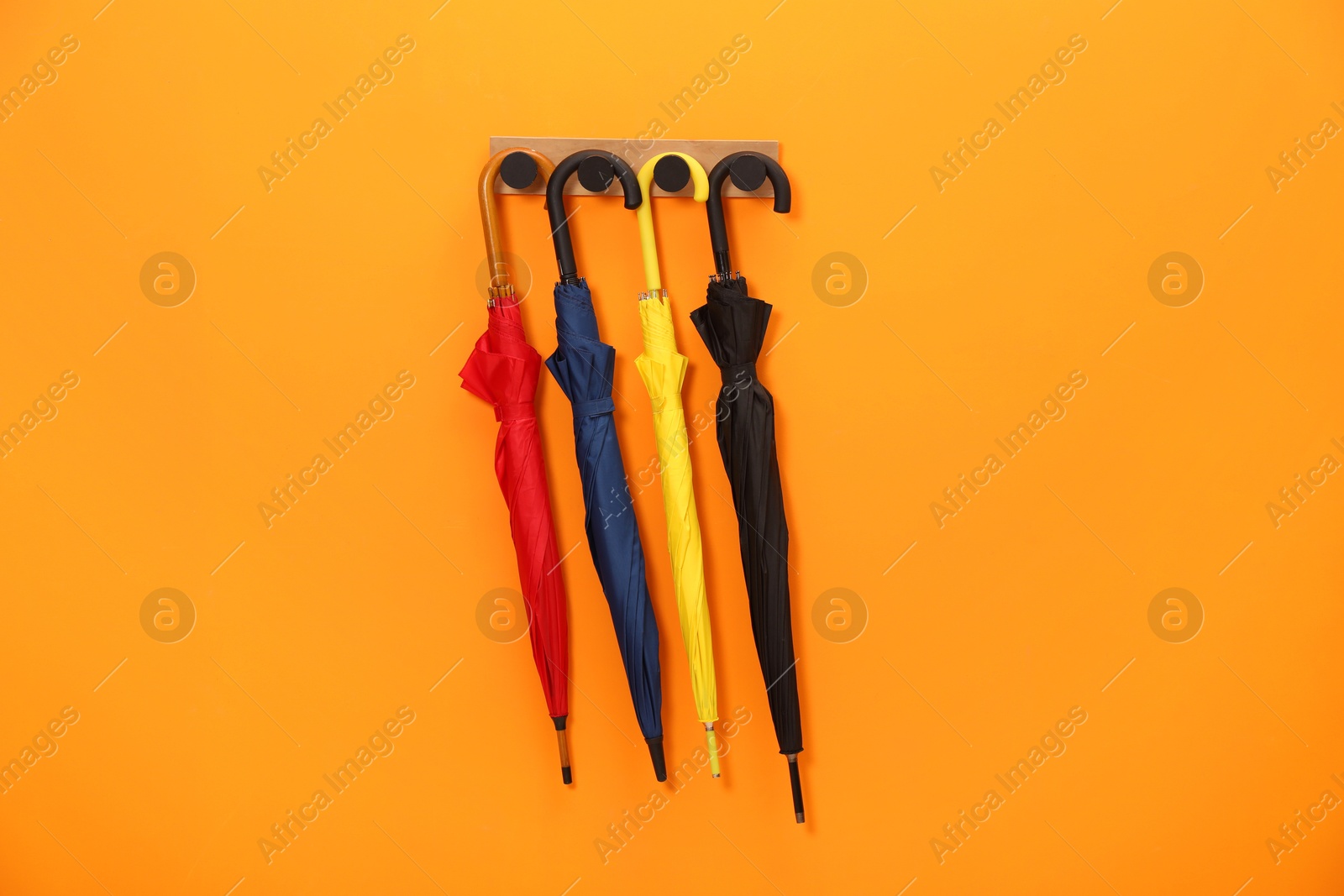 Photo of Colorful umbrellas on wooden rack in hallway