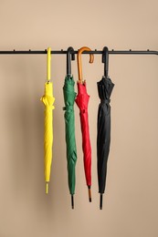 Photo of Colorful umbrellas on rack near beige wall