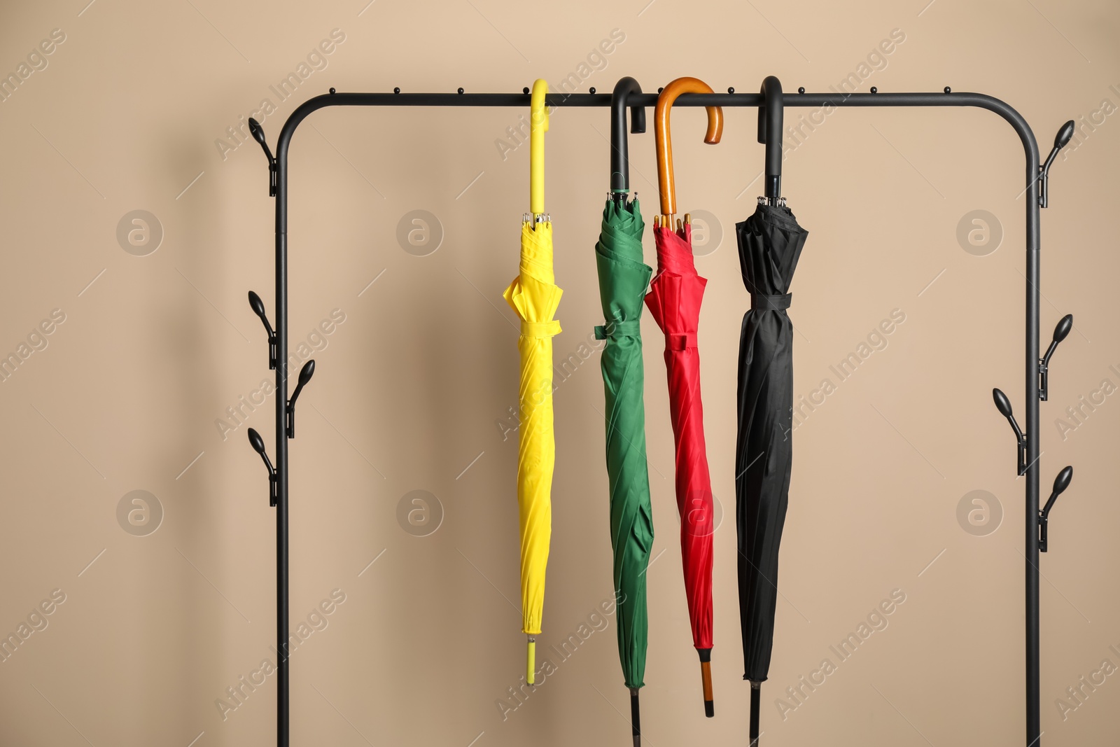 Photo of Colorful umbrellas on rack near beige wall