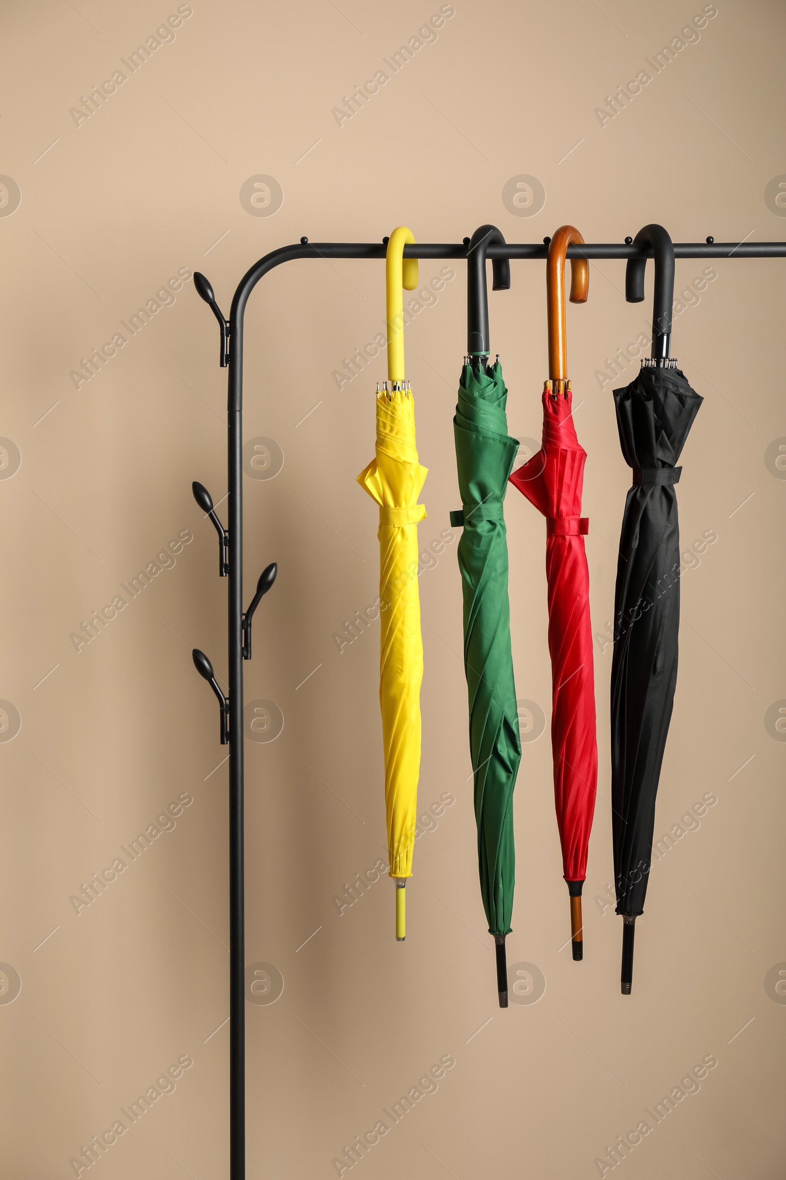 Photo of Colorful umbrellas on rack near beige wall