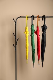 Photo of Colorful umbrellas on rack near beige wall