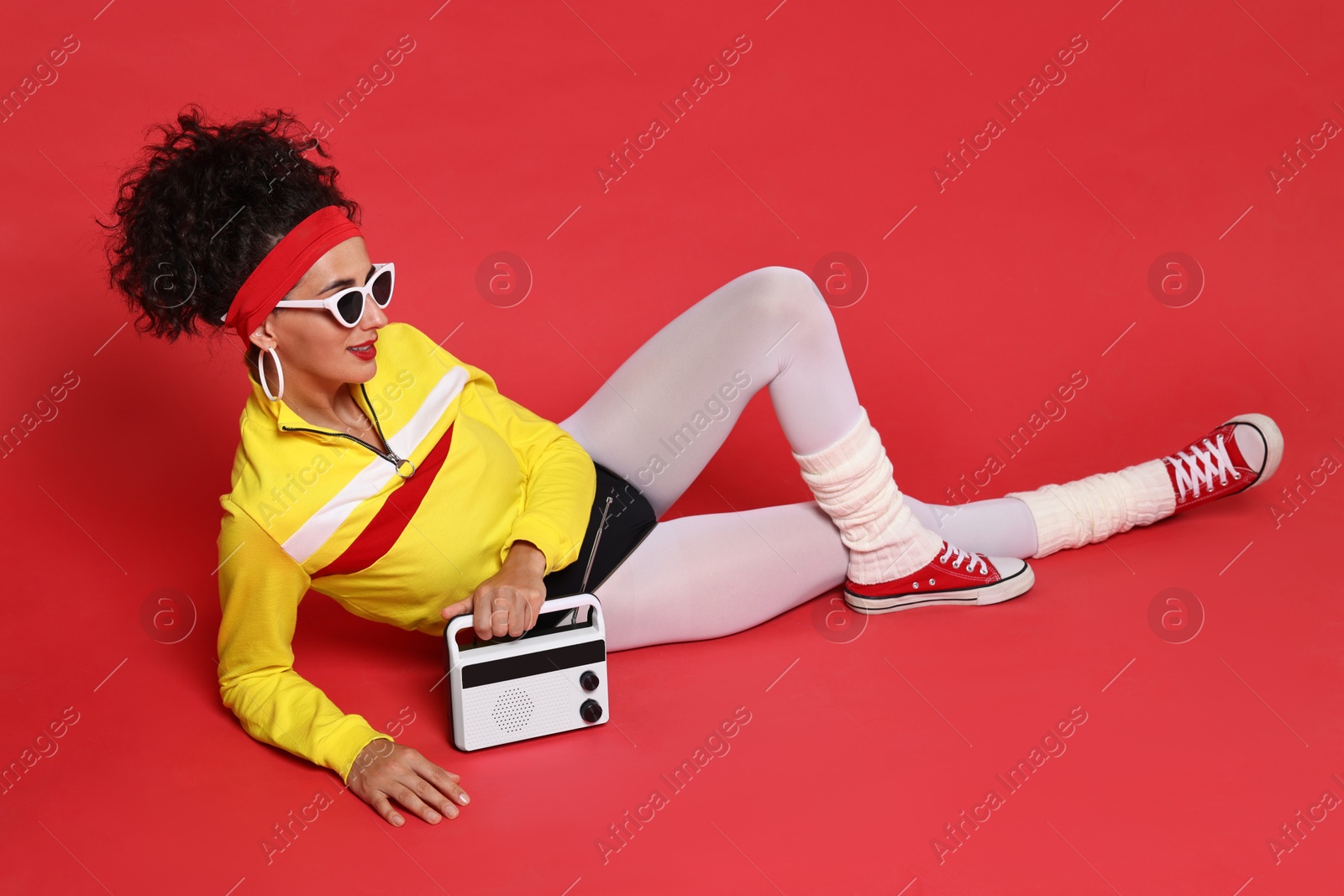 Photo of Aerobics. Woman in sportswear holding radio receiver on red background