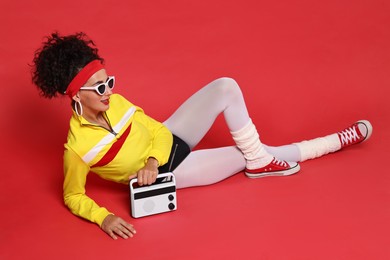 Photo of Aerobics. Woman in sportswear holding radio receiver on red background