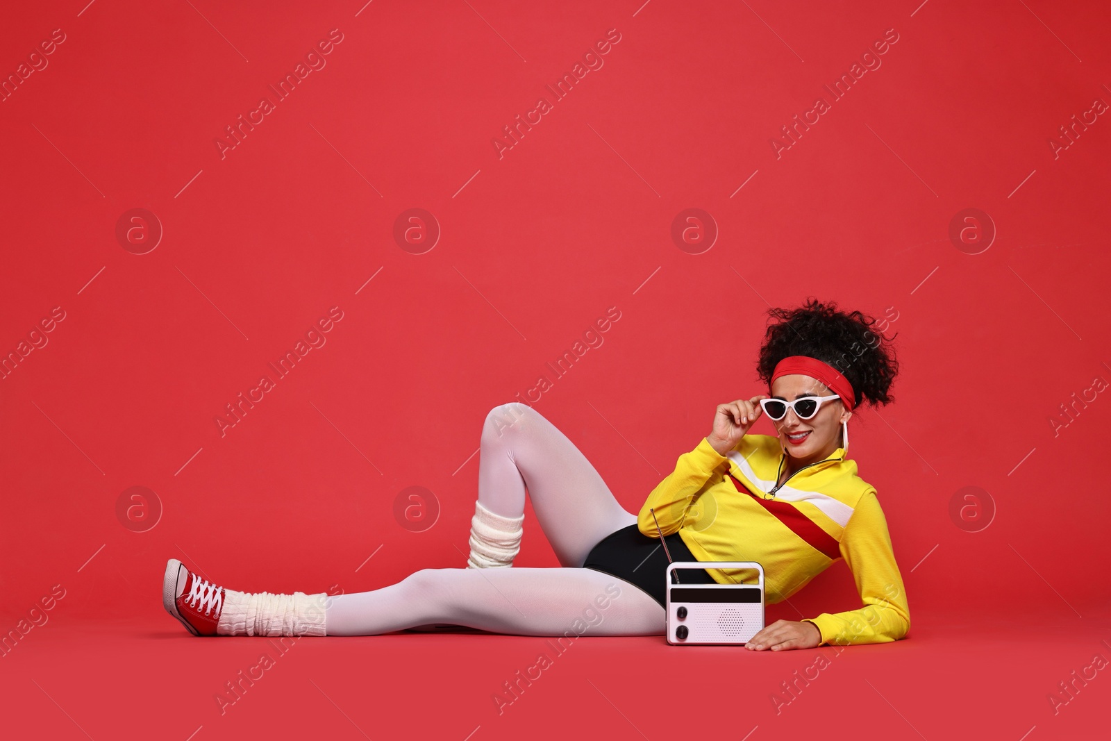 Photo of Aerobics. Woman in sportswear holding radio receiver on red background