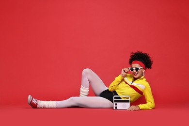 Photo of Aerobics. Woman in sportswear holding radio receiver on red background