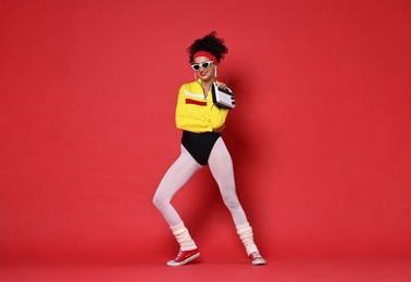 Photo of Aerobics. Woman in sportswear holding radio receiver on red background