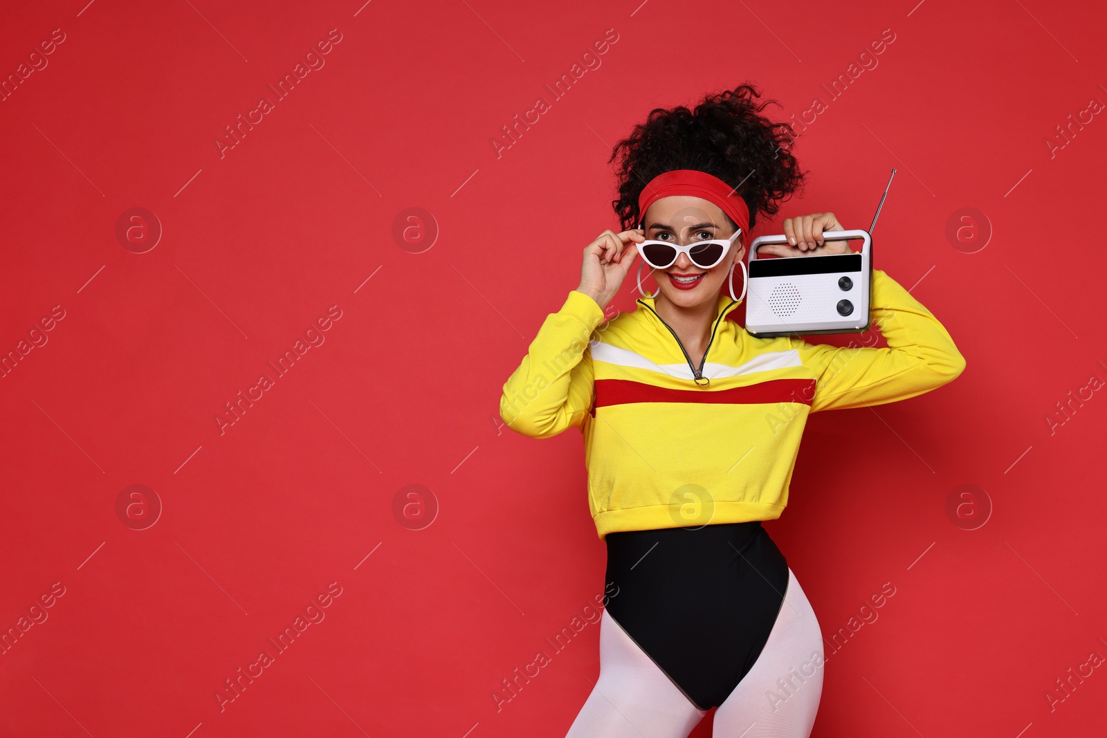 Photo of Aerobics. Woman in sportswear holding radio receiver on red background