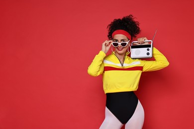 Aerobics. Woman in sportswear holding radio receiver on red background