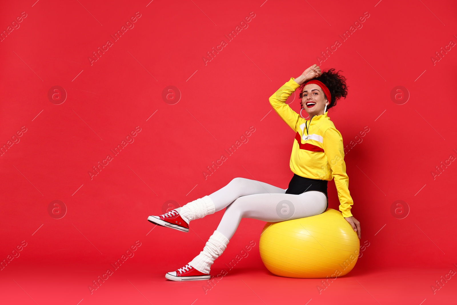 Photo of Aerobics. Happy woman with fitness ball on red background