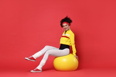 Aerobics. Happy woman with fitness ball on red background