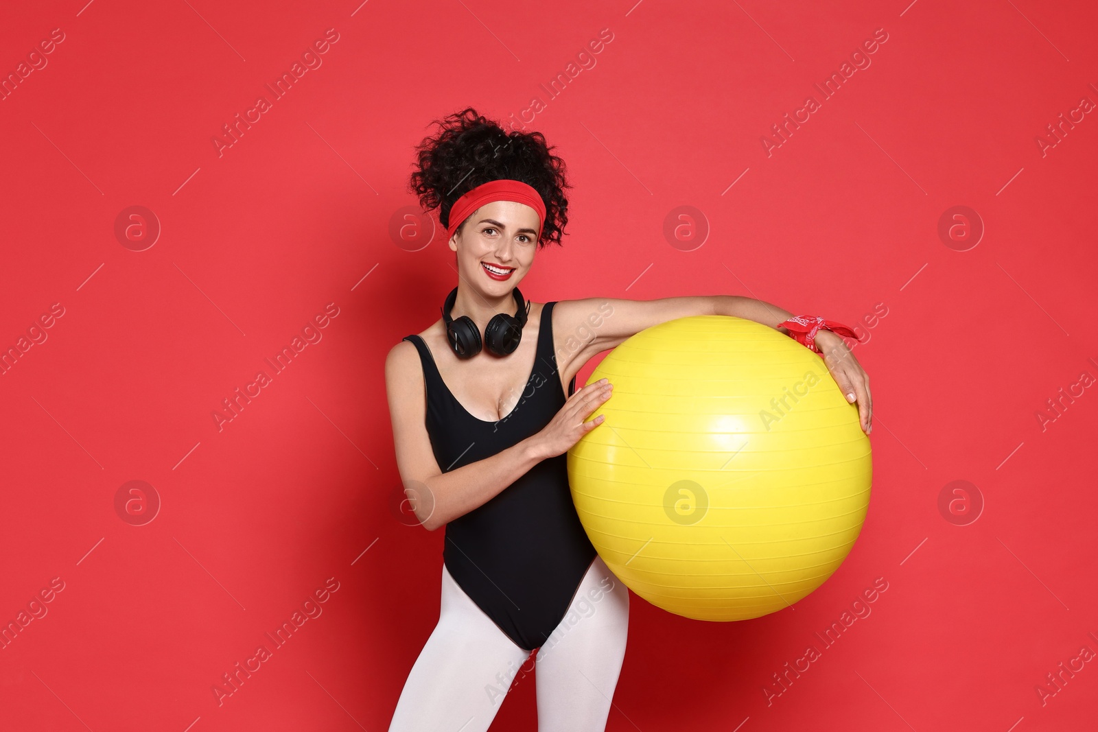 Photo of Aerobics. Happy woman with fitness ball on red background