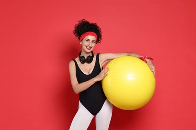 Aerobics. Happy woman with fitness ball on red background