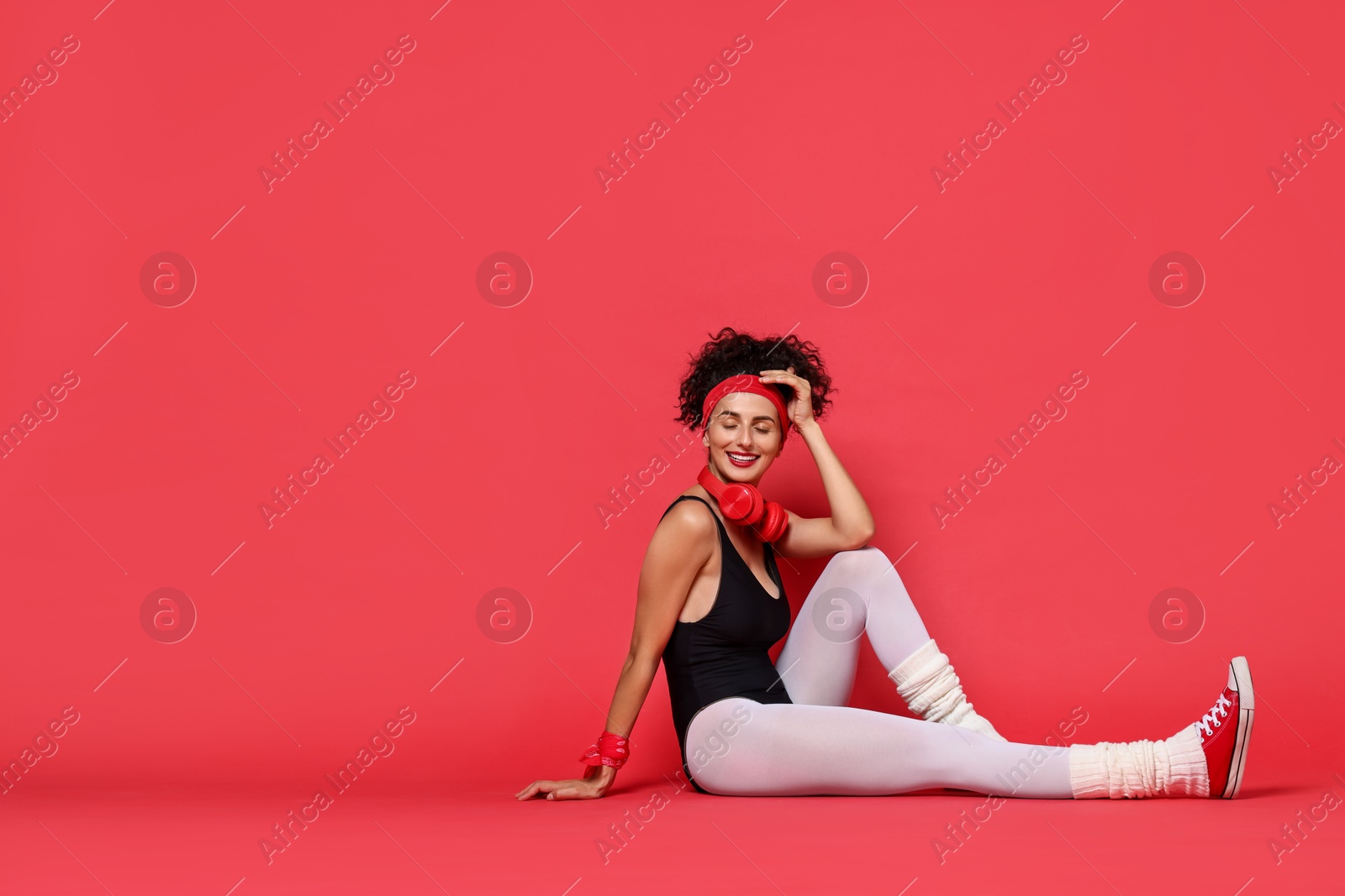 Photo of Aerobics. Happy woman with headphones on red background, space for text