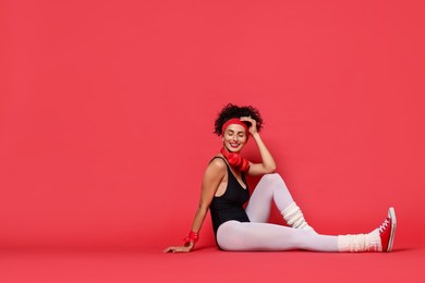 Aerobics. Happy woman with headphones on red background, space for text