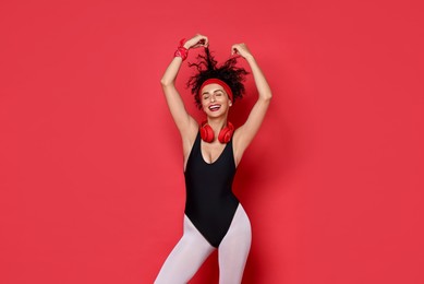 Photo of Aerobics. Happy woman with headphones on red background