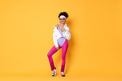 Aerobics. Happy woman in sportswear on orange background