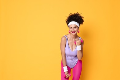 Photo of Woman doing aerobic exercise with dumbbells on orange background, space for text