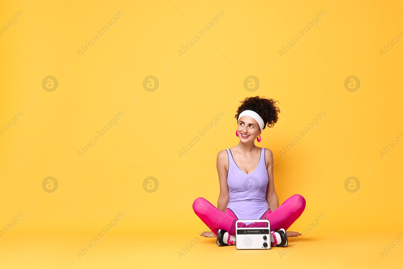 Photo of Aerobics. Woman with radio receiver on orange background