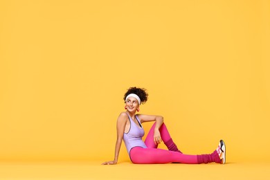 Photo of Happy woman in sportswear on orange background