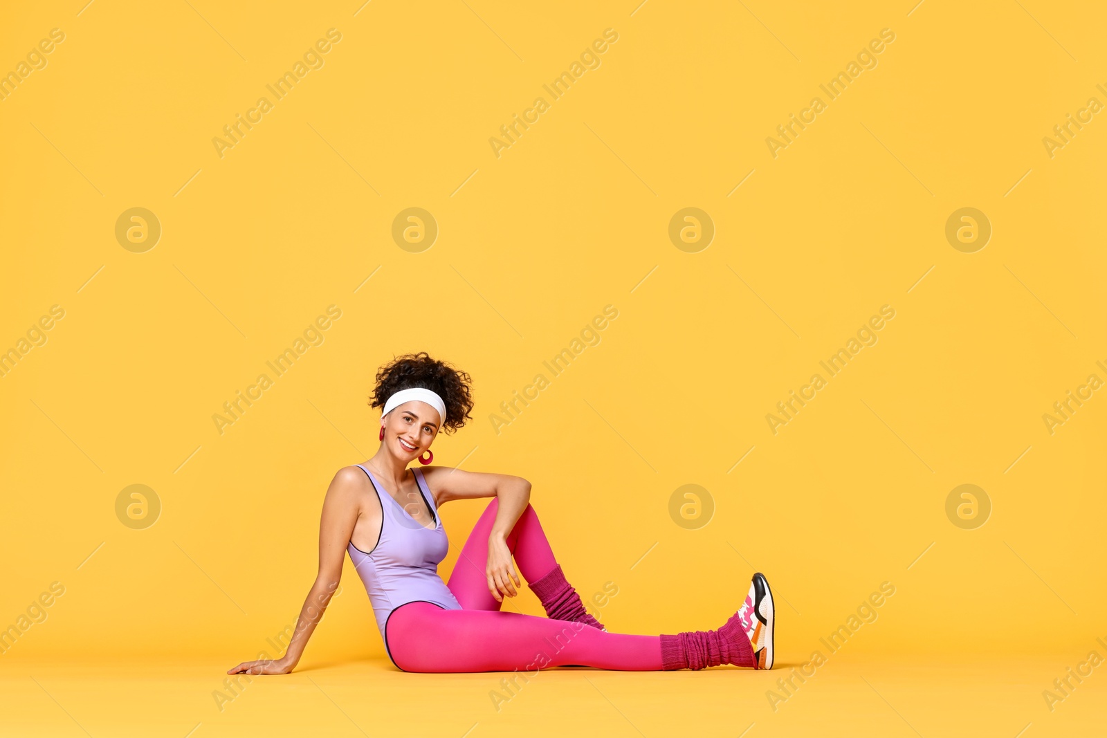 Photo of Happy woman in sportswear on orange background