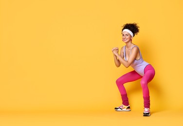 Happy woman doing aerobic exercise on orange background, space for text