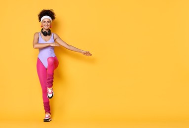 Happy woman doing aerobic exercise on orange background