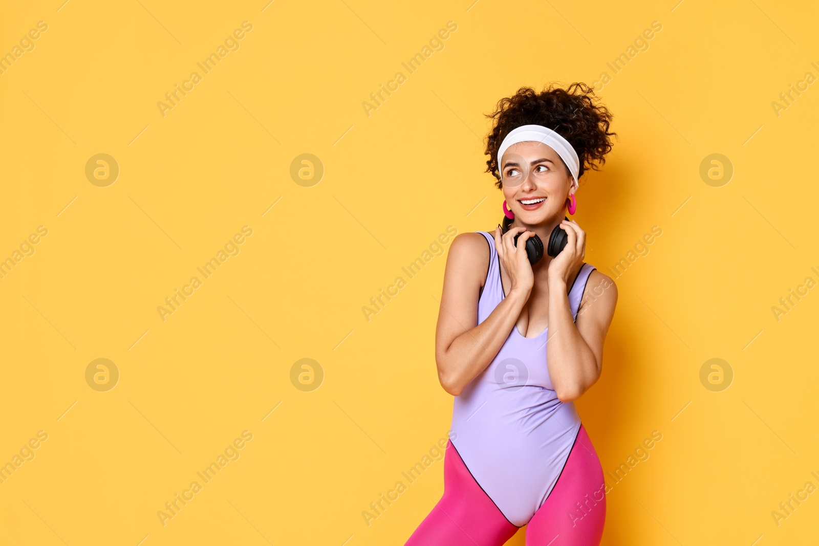 Photo of Happy woman with headphones on orange background, space for text