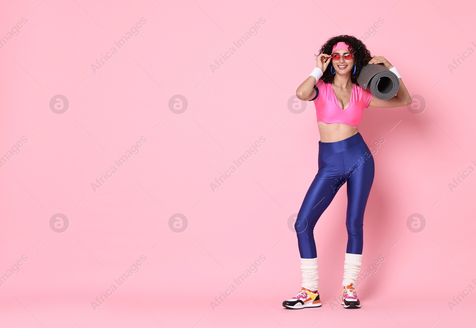 Photo of Aerobics. Happy woman with fitness mat on pink background, space for text