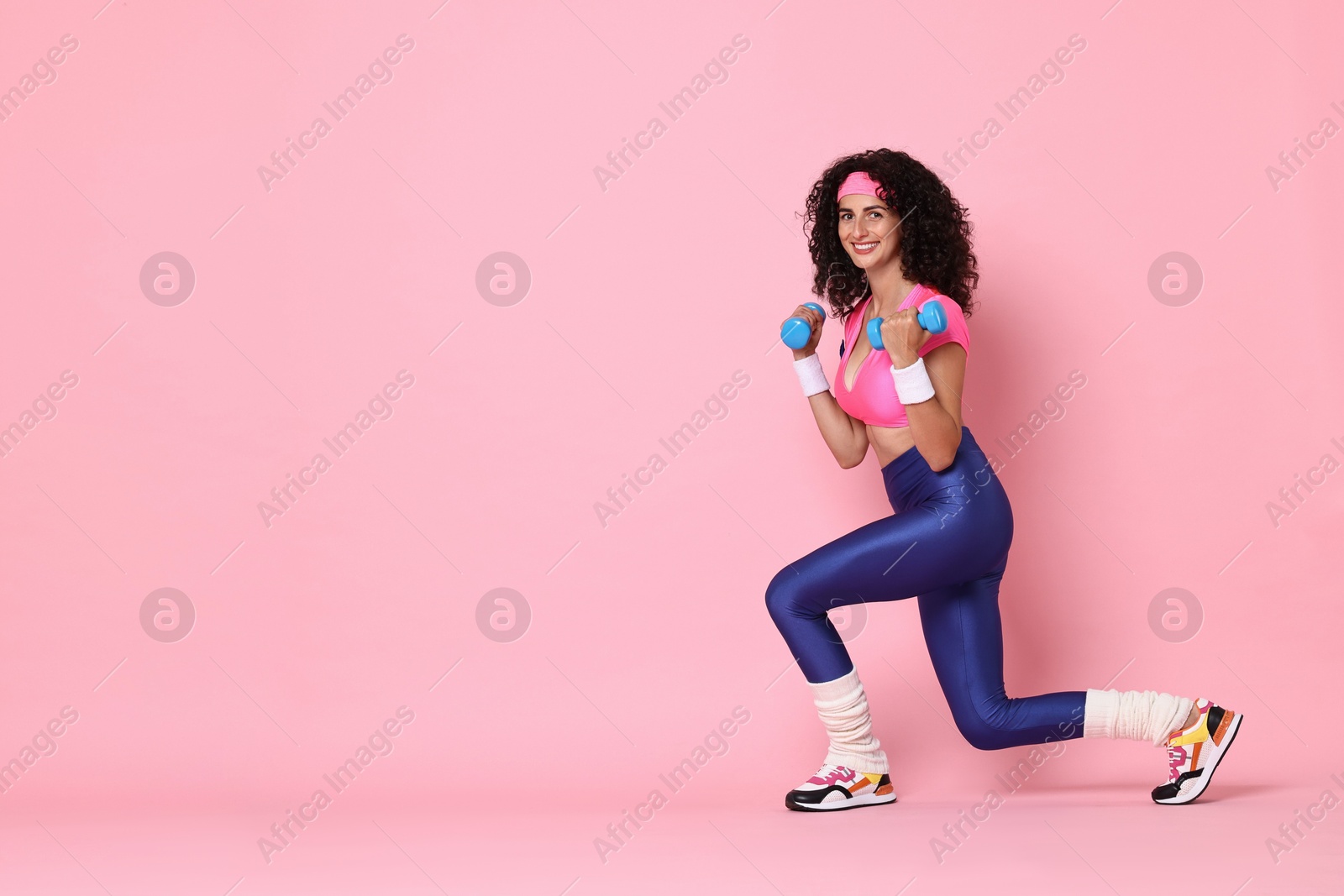 Photo of Woman doing aerobic exercise with dumbbells on pink background, space for text