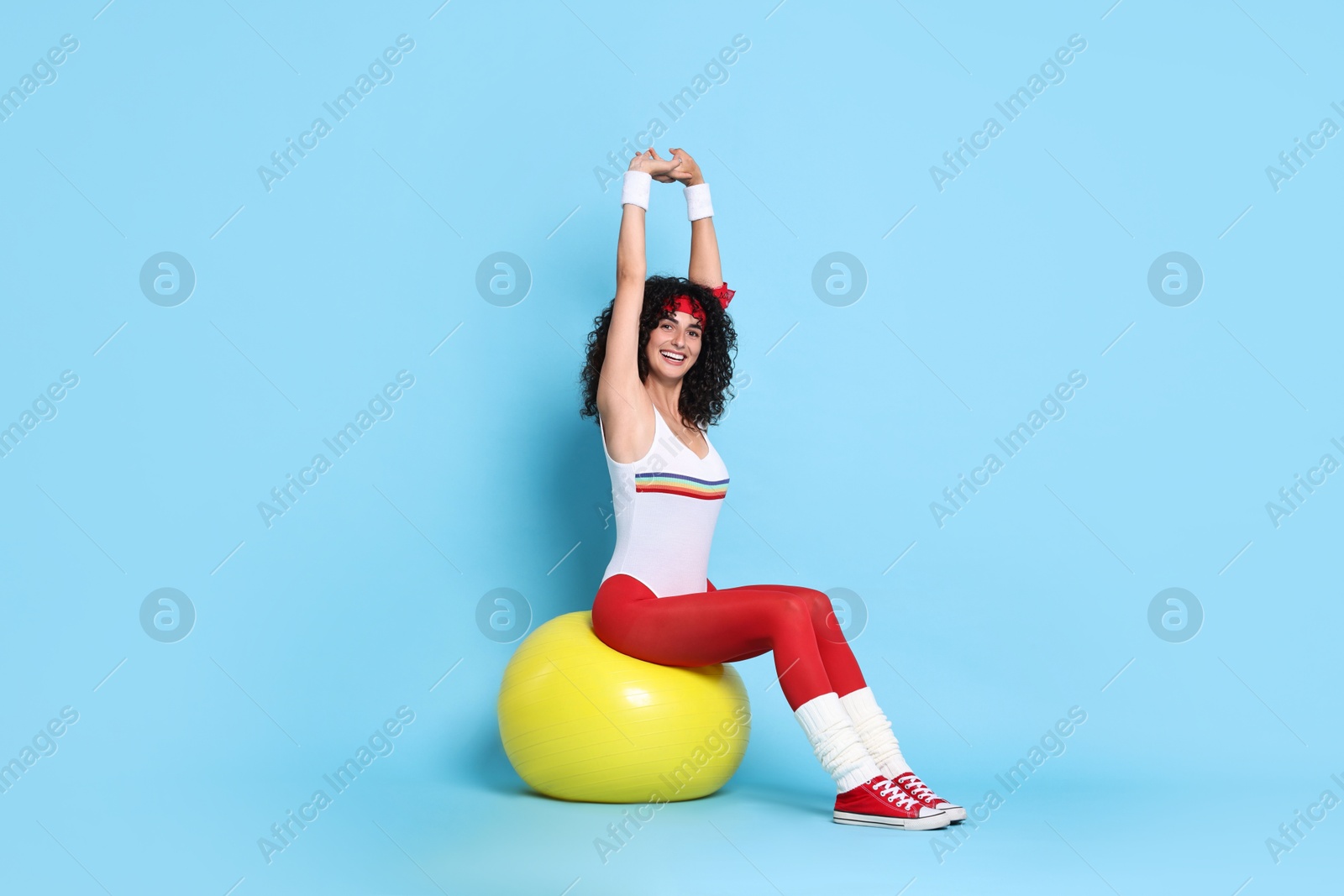 Photo of Aerobics. Happy woman with fitness ball on light blue background