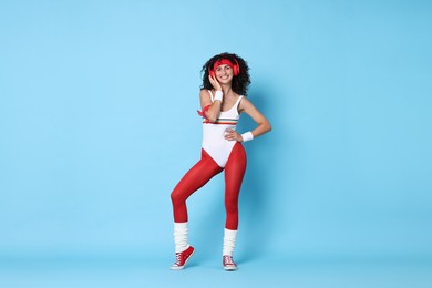 Photo of Aerobics. Happy woman in headphones on light blue background