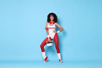 Photo of Aerobics. Happy woman with radio receiver on light blue background