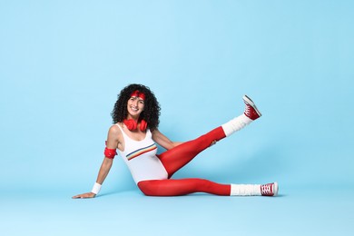 Aerobics. Happy woman with headphones on light blue background