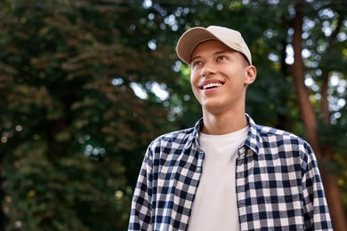 Photo of Portrait of smiling man in baseball cap outdoors, low angle view. Space for text