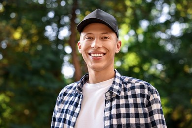 Portrait of smiling man in baseball cap outdoors. Space for text