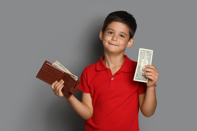 Photo of Cute boy with wallet and pocket money on grey background