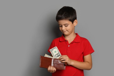 Photo of Cute boy with wallet and pocket money on grey background, space for text