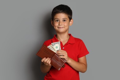 Photo of Cute boy with wallet and pocket money on grey background